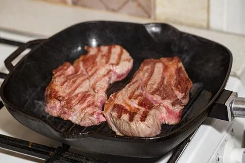 Raw beef steak in grill pan Stock Photos