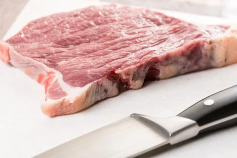 Raw beef steak on the marble table with chef knife Stock Photos