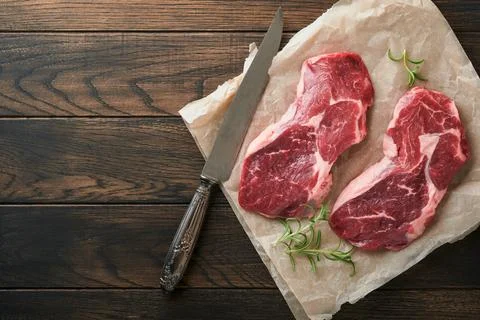 Raw beef steak. Marbled raw fresh Ribeye steak with rosemary, salt and pepper Stock Photos