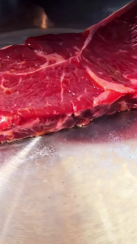 Raw beef steak marbling close-up view on a stainless steel kitchen frying pan Stock Footage 337183328