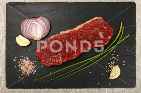 Raw beef steak meat cut and spices on black board Stock Photos