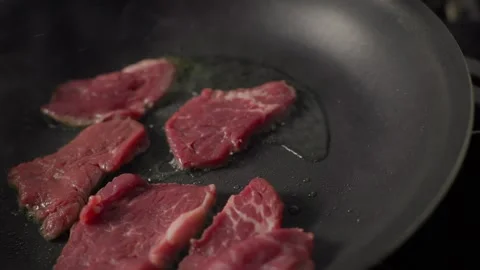 Raw beef steak placed into hot pan with oil on gas stove Stock Footage 313055788