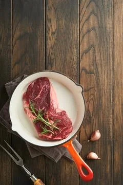 Raw beef steak. Raw fresh Ribeye steak with rosemary, salt and pepper in iron Stock Photos