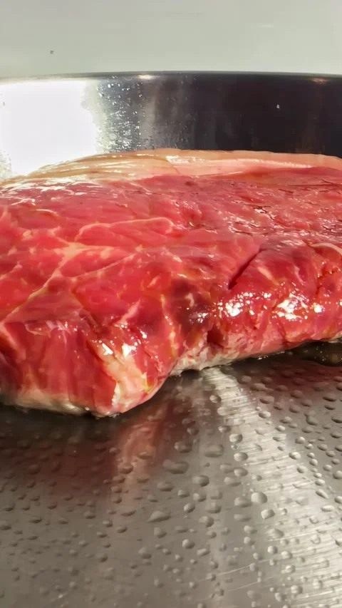 Raw Beef Steak Sizzling Slowly on Hot Stainless Steel Grill Stock Footage 339752080