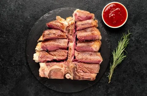 Raw beef steak slices on black plate with ketchup and rosemary Stock Photos