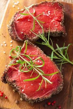 Raw beef steak with spices and rosemary on wooden background Stock Photos
