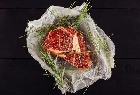 Raw beef steak with spices on baking paper Stock Photos