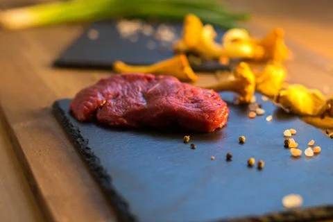 Raw beef steak on a stone slab decorated with chanterelle mushrooms Stock Photos