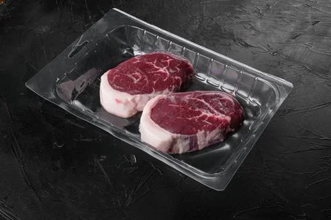 Raw beef steak in vacuum package, on black dark stone table background, with  Stock Photos