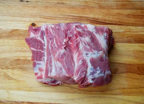 Raw beef steak with visible fat marbling on a wooden cutting board Stock Photos