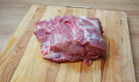 Raw beef steak with visible fat marbling on a wooden cutting board Stock Photos