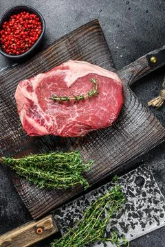 Raw beef striploin on the bone meat steak. Black ground. Top view Stock Photos