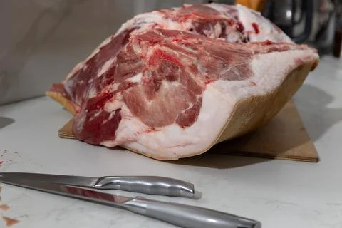 Raw bone-in pork leg deboning in a home kitchen: authentic butcher realism Stock Photos