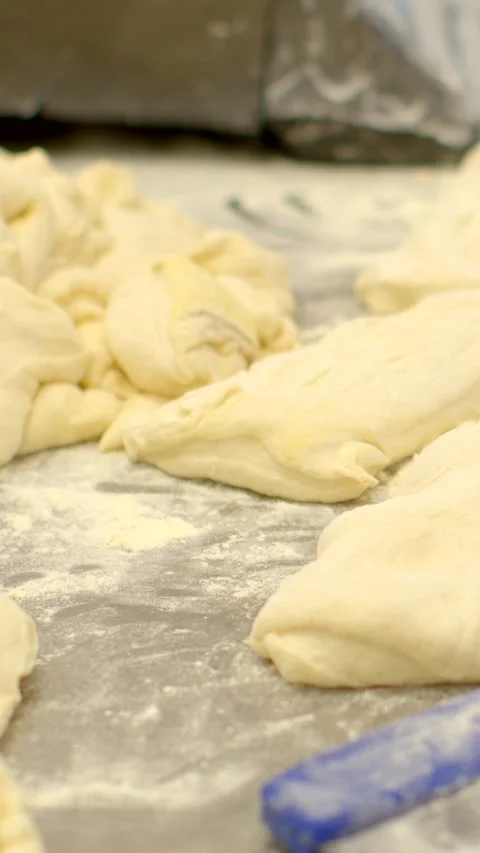 Raw bread dough pieces on floured work surface in bakery preparation line Видео 344574729