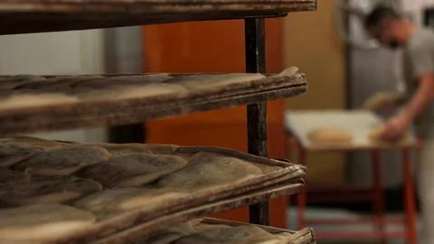 Raw bread dough resting on trays in a bakery Stock Photos