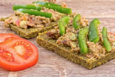 Raw bread with a spread decorated with pepper and tomatoes 스톡 사진