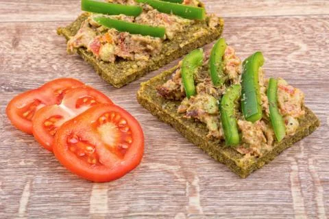 Raw bread with a spread decorated with pepper and tomatoes Stock Photos