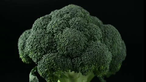 Raw broccoli head rotating over black background. Video stock 273794427