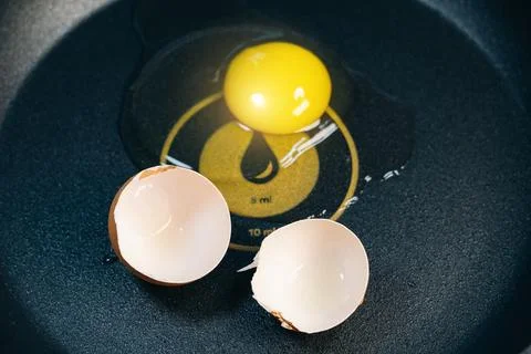 Raw broken egg and egg shells in a pan with a dispenser. Expensive price on.. Stock Photos