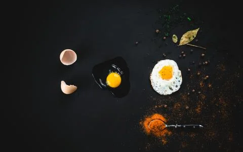 Raw broken egg and fried on a black background. Concept: from raw to finished Stock Photos