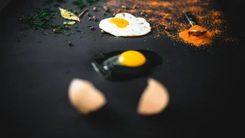 Raw broken egg and fried on a black background. Concept: from raw to finished Stock Photos