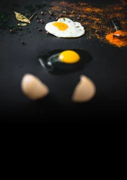 Raw broken egg and fried on a black background and place for text. Concept: T Stock Photos