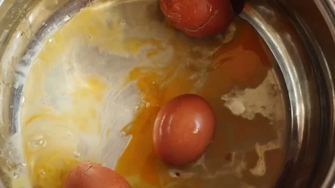 A raw brown chicken egg falls into a metal pot from above onto several brok.. Stock Footage 344112503