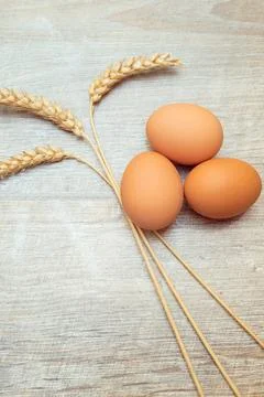 Raw brown chicken eggs with spikelets on a wooden table. Easter rustic Foto stock