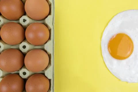 Raw brown eggs pack and a fried sunny side egg on yellow background Stock Photos