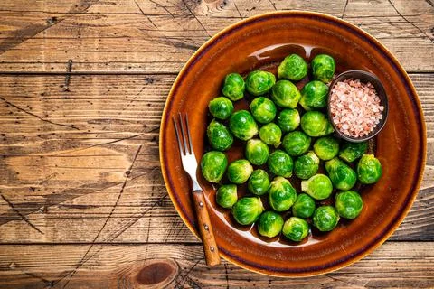 Raw Brussels green sprouts cabbage in a rustic plate with salt. wooden Stock Photos