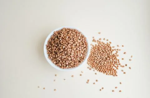 Raw buckwheat in a cup on a light background Stock Photos