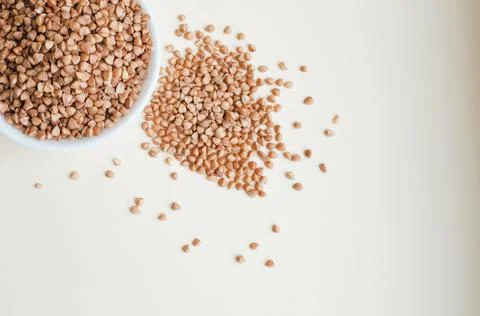 Raw buckwheat in a cup on a light background Stock Photos