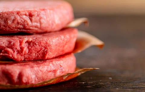 Raw burger on paper. On a rustic dark background. Stock Photos