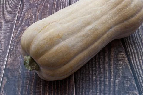 A raw butternut squash gourd on a rustic wooden table surface. Stock-Fotos