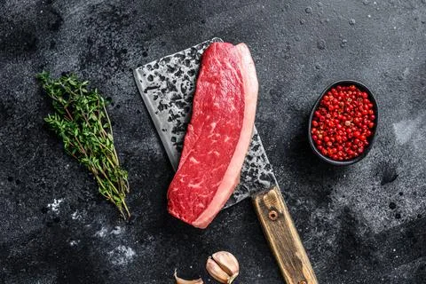 Raw cap rump beef meat steak on a butcher cleaver. Black background. Top view Stock Photos