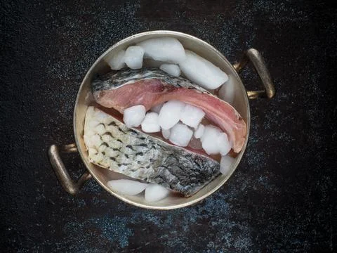 Raw carp fillets on ice in silver bowl. Stock Photos