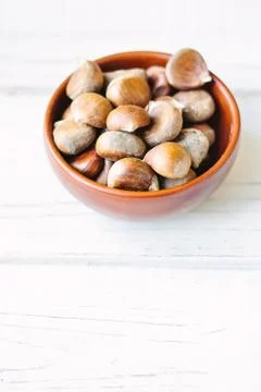 Raw chestnuts in ceramic bowl. Stock Photos