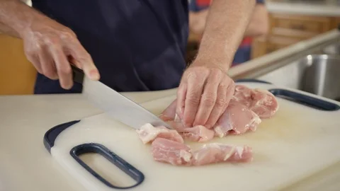 Raw chicken being sliced by male hands on cutting board Stock Footage 123734049