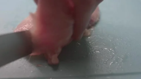 A raw chicken breast is being pounded on a cutting board for the purpose of tend Stock Footage 297202255