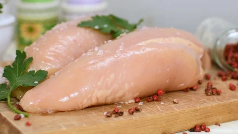 Raw chicken breast with cherry tomatoes and parsleyon wood cuttingboard. Stock-Footage 125233444
