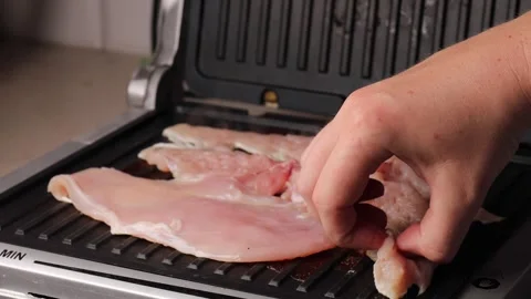 Raw chicken breasts being placed on an electric grill for cooking Stock Footage 292645388