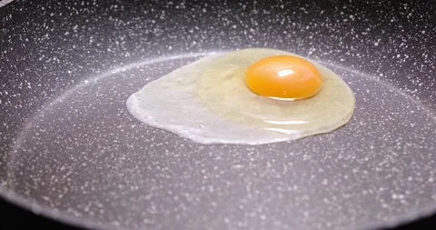 A raw chicken egg falls into a frying pan. Diet cooking, healthy eating. Stock Footage 151914199