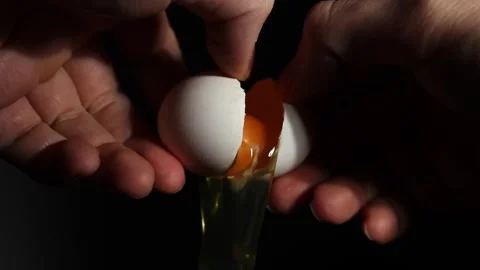 Raw chicken egg pouring out of shell close-up slow motion. Stock Footage 303600159