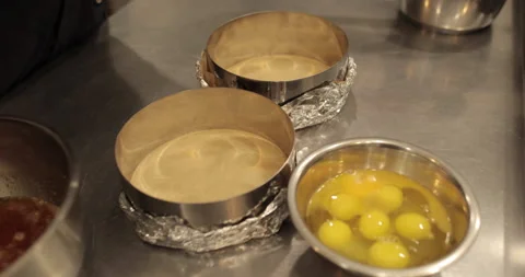Raw chicken eggs are broken into a metal bowl on the table Stock Footage 256982412