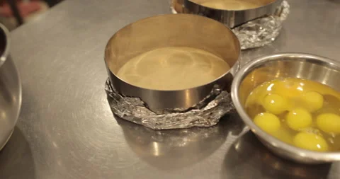 Raw chicken eggs are broken into a metal bowl on the table Stock Footage 256982754