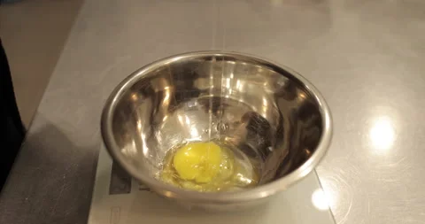 Raw chicken eggs are broken into a metal bowl on the table Stock Footage 256982903