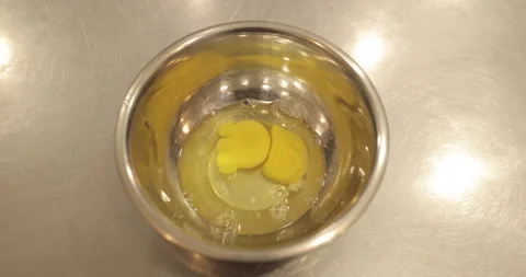 Raw chicken eggs are broken into a metal bowl on the table Stock Footage 256983109