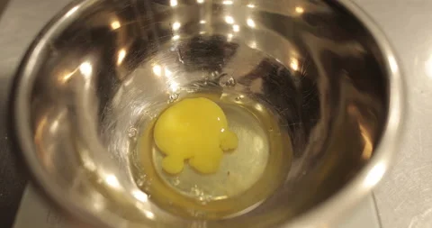 Raw chicken eggs are broken into a metal bowl on the table Stock Footage 256983172