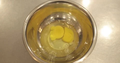Raw chicken eggs are broken into a metal bowl on the table Stock Footage 256983282