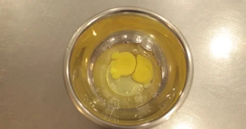 Raw chicken eggs are broken into a metal bowl on the table Stock Footage 256983362